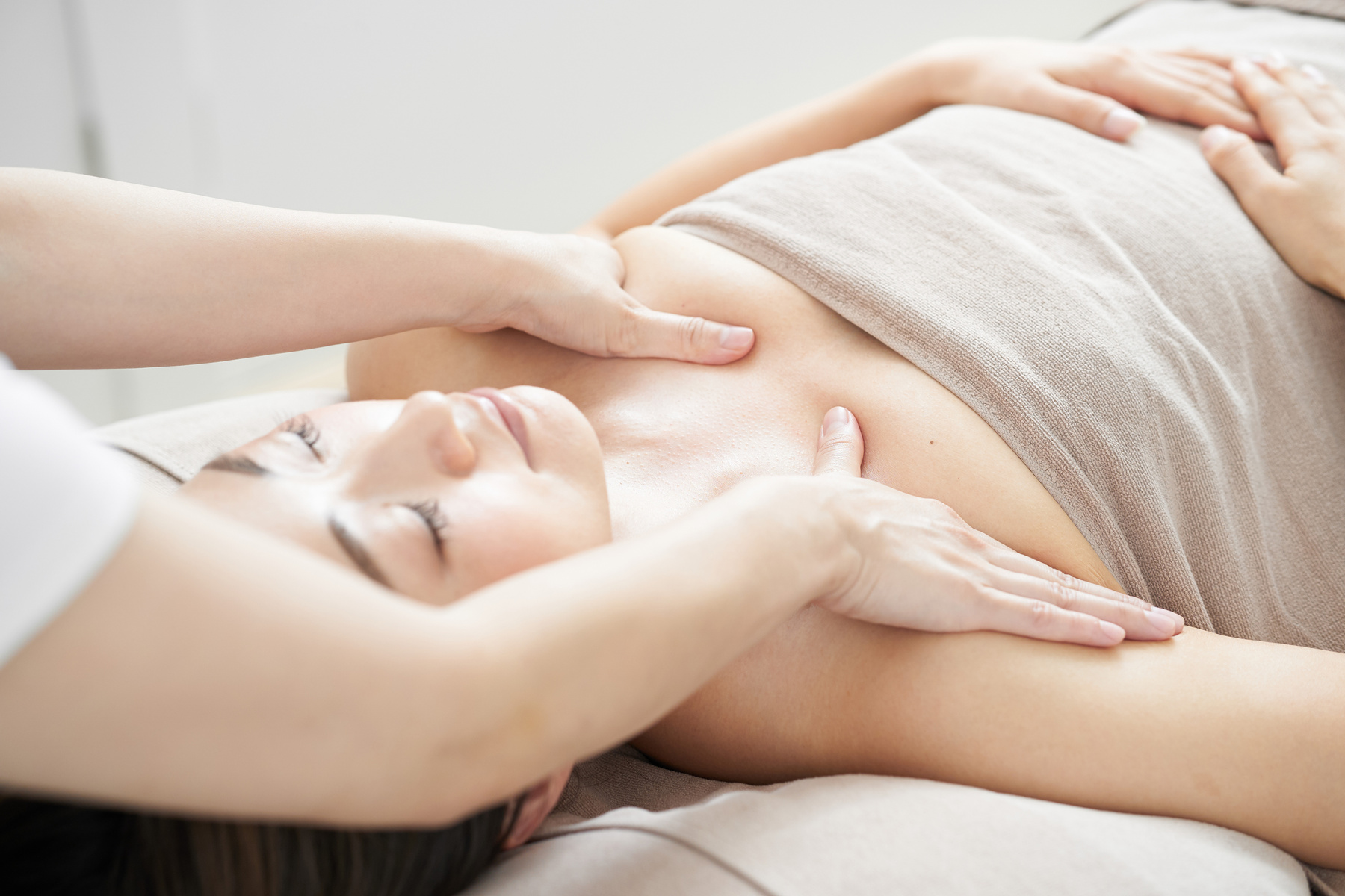 Woman receiving decollete massage in bright beauty salon